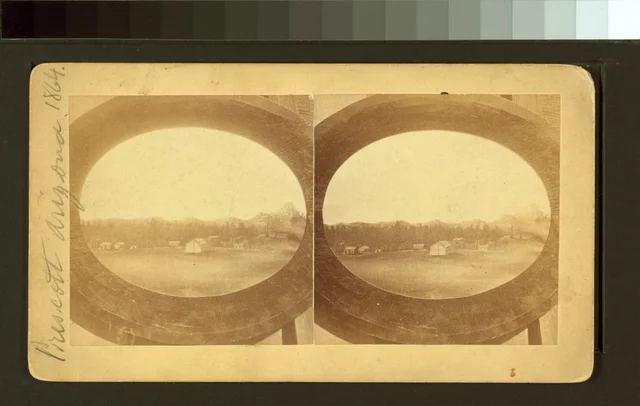 Paired stereograph showing a few buildings and wooded hills in early Prescott